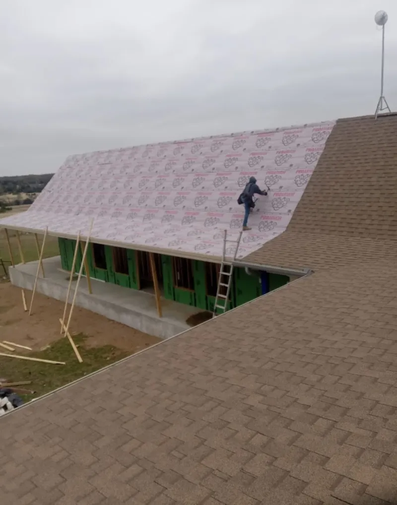 Worker preparing underlayment for a metal roof installation in Bridgeport